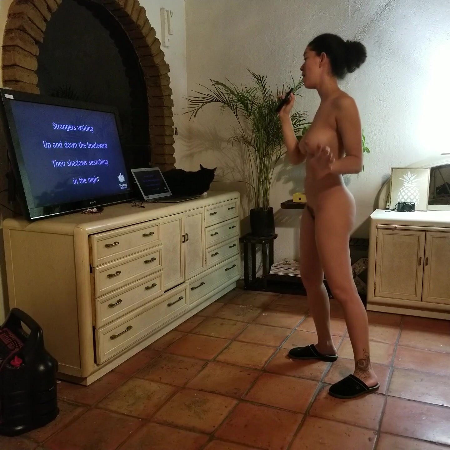 Mujer haciendo karaoke desnudo en casa